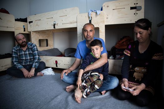 GREECE, Skaramagas: As thousands of refugees remain stranded in Greece, a family sits in one of several storage containers serving homes for 1,000 people at a new camp in Skaramagas, near Athens on April 14, 2016. They have just been relocated here after being stranded at the port of Piraeus, where they originally landed.