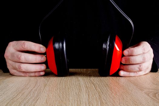 Ear protectors in human hand.  On a wooden surface.