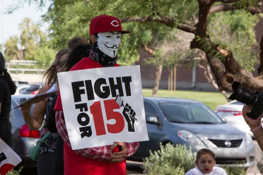 UNITED STATES, Phoenix: A protester holds a sign reading 'Fight for 15' as hundreds of workers and supports took to the streets in Phoenix, Arizona on April 14, 2016 to call for a national minimum wage increase to  an hour. 