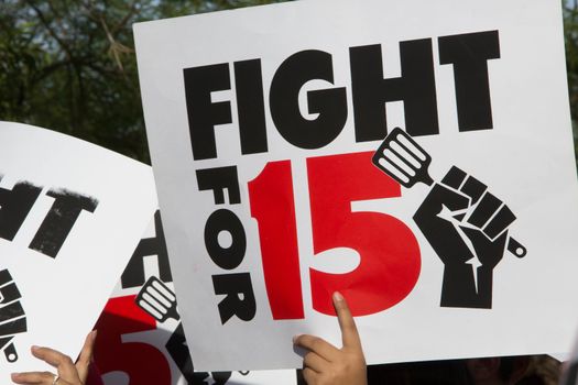 UNITED STATES, Phoenix: A protester holds a sign reading 'Fight for 15' as hundreds of workers and supports took to the streets in Phoenix, Arizona on April 14, 2016 to call for a national minimum wage increase to  an hour. 