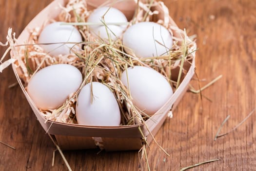 chicken eggs in basket on wooden background
