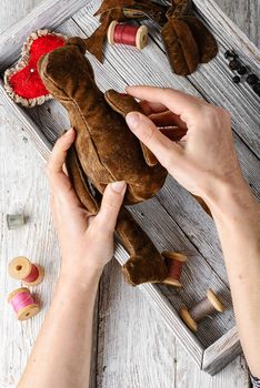 Women's hands in the process of manufacturing soft bear toys and sewing tools