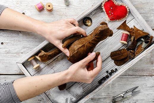 Women's hands in the process of manufacturing soft bear toys and sewing tools