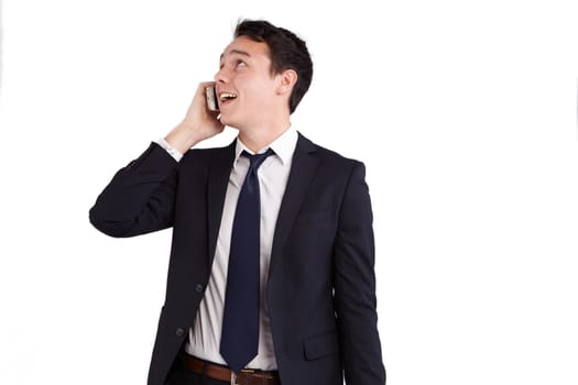 A young caucasian male businessman smiling holding a mobile phone looking away from camera.