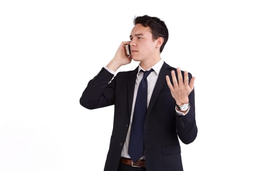 A young caucasian male businessman frowns with raised hand while holding a mobile phone looking away from camera.