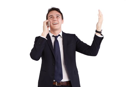 A young caucasian male businessman smiling with raised hand holding a mobile phone looking away from camera.