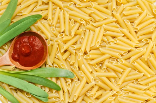 The paste on the surface, background, pasta, green onions and ketchup in a wooden spoon.