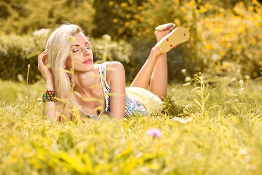 Beauty playful woman relax in summer garden dreaming on grass, people, outdoors, bokeh. Attractive happy blonde girl enjoying nature, harmony on meadow, lifestyle.Sunny day, forest, flowers, copyspace