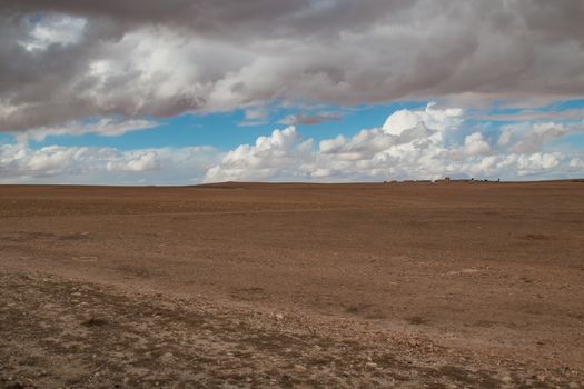 Autumn field with a light color of the dry soil. Big stormy clouds before a rain. Country close to Marrakesh.