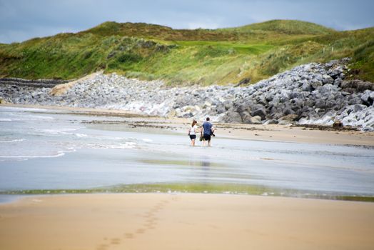 loving couple with dog paddeling on ballybunion beach