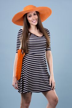 young woman wearing dress and orange hat on blue background