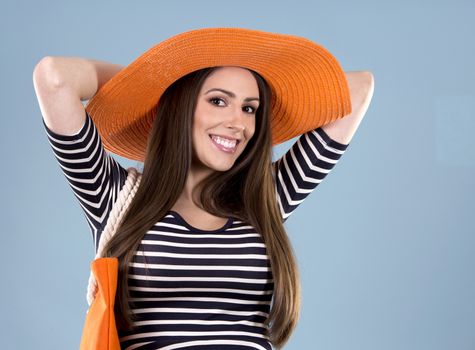 young woman wearing dress and orange hat on blue background