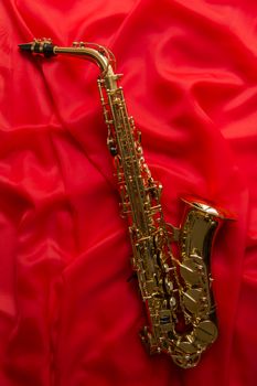 beautiful golden saxophone on the texture of the from delicate silk Red
