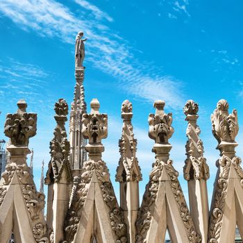 White marble statues on the roof of famous Cathedral Duomo di Milano on piazza in Milan, Italy