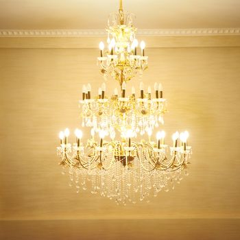 Beautiful crystal ancient chandelier in a hall. Lamp with soft yellow light
