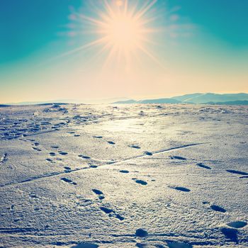Footprints on the snow. Bright landscape with sun in winter mountains. Instagram like filter