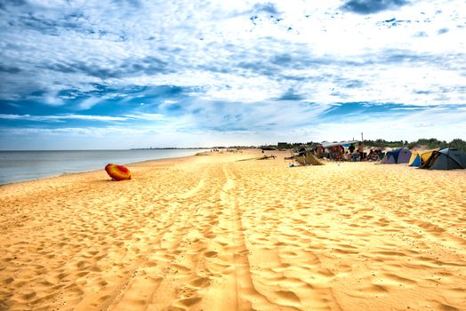 Camping on the sandy beach. Blue sea and sunset clouds on background