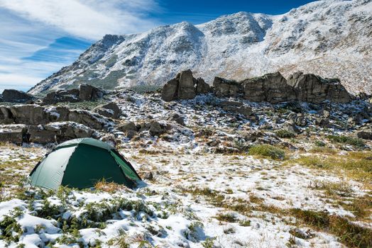 Green tent in snow mountains. Beautiful spring landscape
