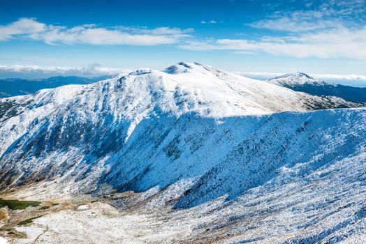 Green valley and white peaks of mountains in snow. Winter landscape