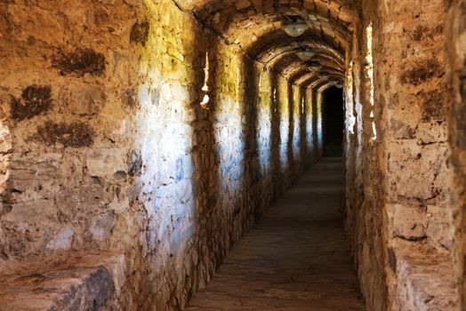 Dark corridor in dungeon with light in the end