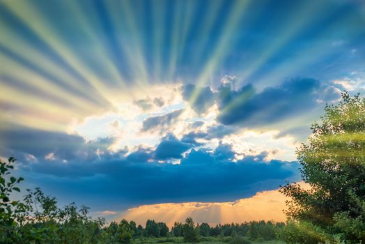 Colorful sunset outside. Blue clouds and many sun rays