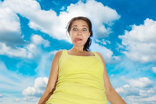 Pretty young girl with funny face expression over blue sky with clouds