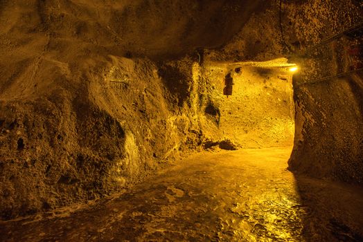 Dark underground corridor in a dungeon with light at exit