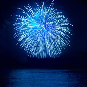 Blue ball fireworks above lake with reflection on water with black sky background
