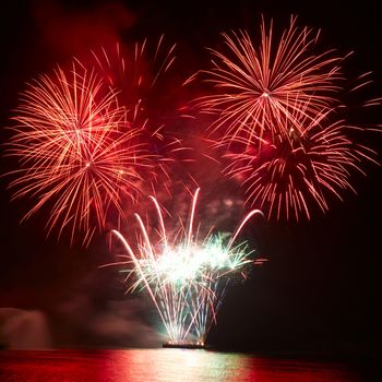 Beautiful colorful red and orange holiday fireworks on the black sky background