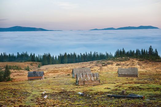 Old house in front of beautiful nature with clouds ocean, field of grass and mountains