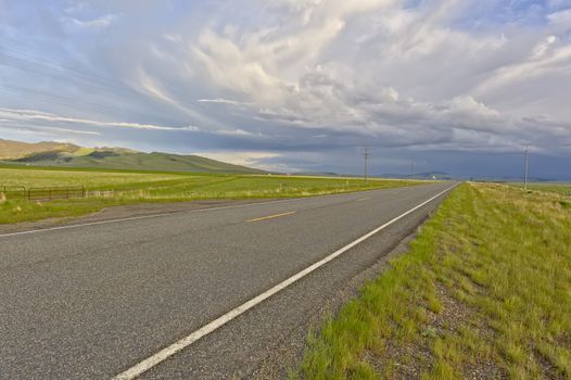 A thunderstorm building up in the distance over a deserted road in Montana.