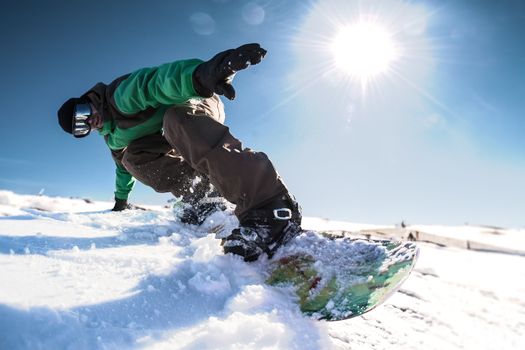 Snowboard freerider in the mountains against sun shine in blue sky.