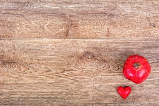 Pomegranate and red heart on a wooden background