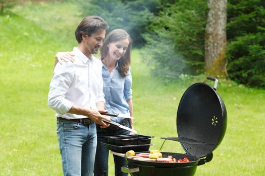 Happy couple cooking food on barbecue