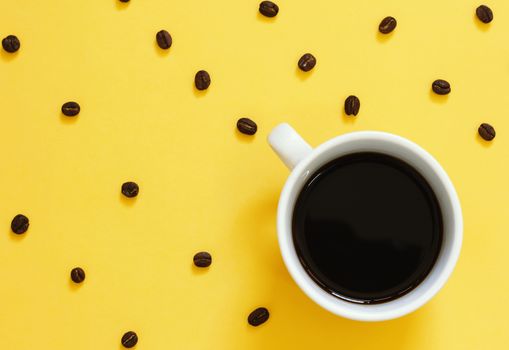 Top view of black coffee and coffee beans on yellow background