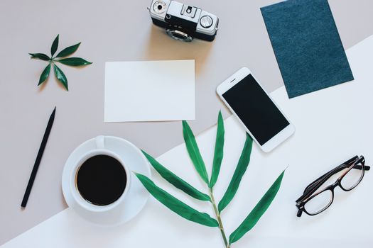 Creative flat lay photo of workspace desk with smartphone, coffee, film camera, blank paper and envelope with copy space background, minimal style
