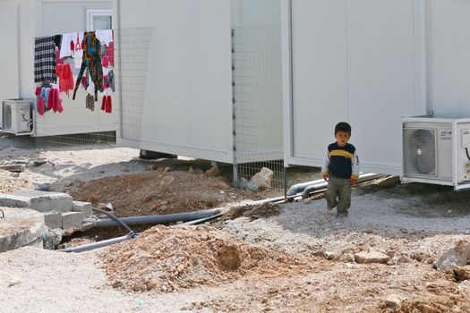 GREECE, Athens: A young boy walks through the construction near his new prefabricated home at Skaramagas camp on April 14, 2016 in Greece.