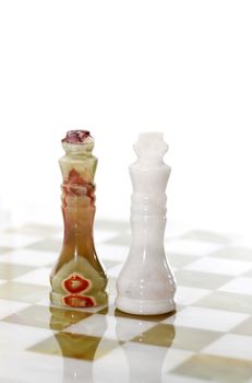 Pair of chess Kings made from Onyx on board against white background