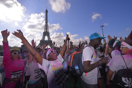 FRANCE, Paris : People participate in the Color Run 2016 in front of the Eiffel Tower in Paris on April 17, 2016.The Color Run is a five kilometres paint race without winners nor prizes, while runners are showered with colored powder at stations along the run. 