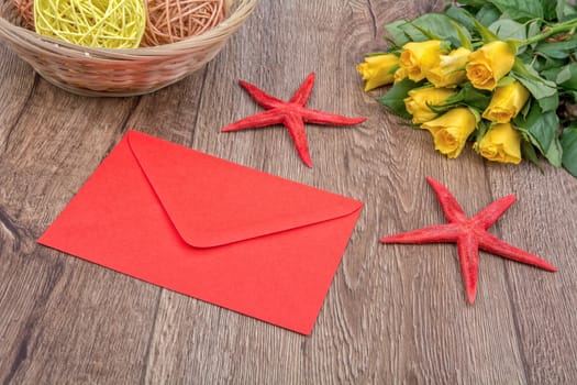 Envelope, red starfishes and roses on a wooden background