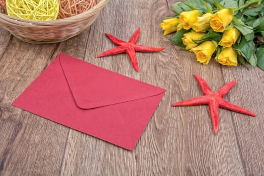 Envelope, red starfishes and roses on a wooden background