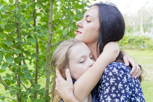Embracing mother and daughter in summer on green background