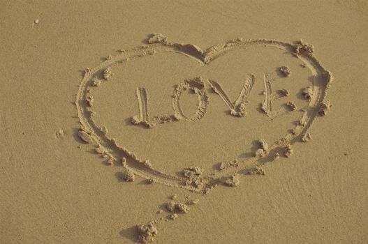 Heart sign and word love on sand in vintage style.