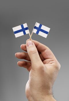 Man holding two small flags of Finland in his hand.
