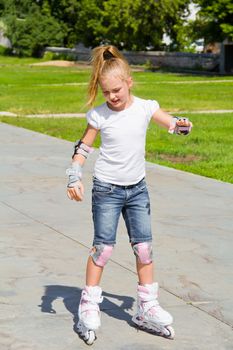 Learning girl on roller skates in summer