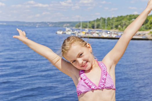 Dancing girl on the riverbank in pink swimsuit