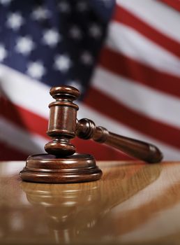 Wooden gavel on glossy table, The flag of USA in the background.