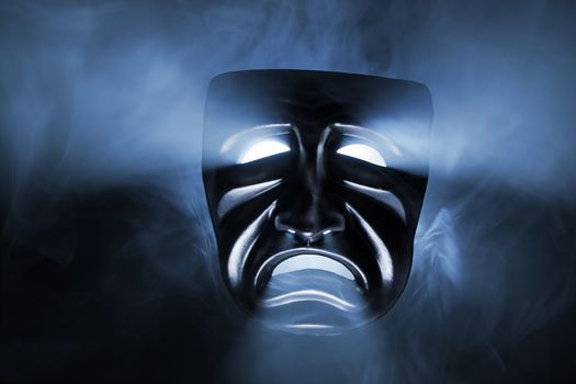 Black mask with light coming from its eyes and mouth.