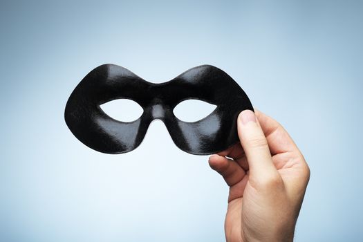Man holding a black eyemask in his hand.