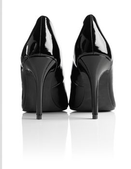 Black shiny patent leather stiletto heel pumps isolated on white with natural reflection.